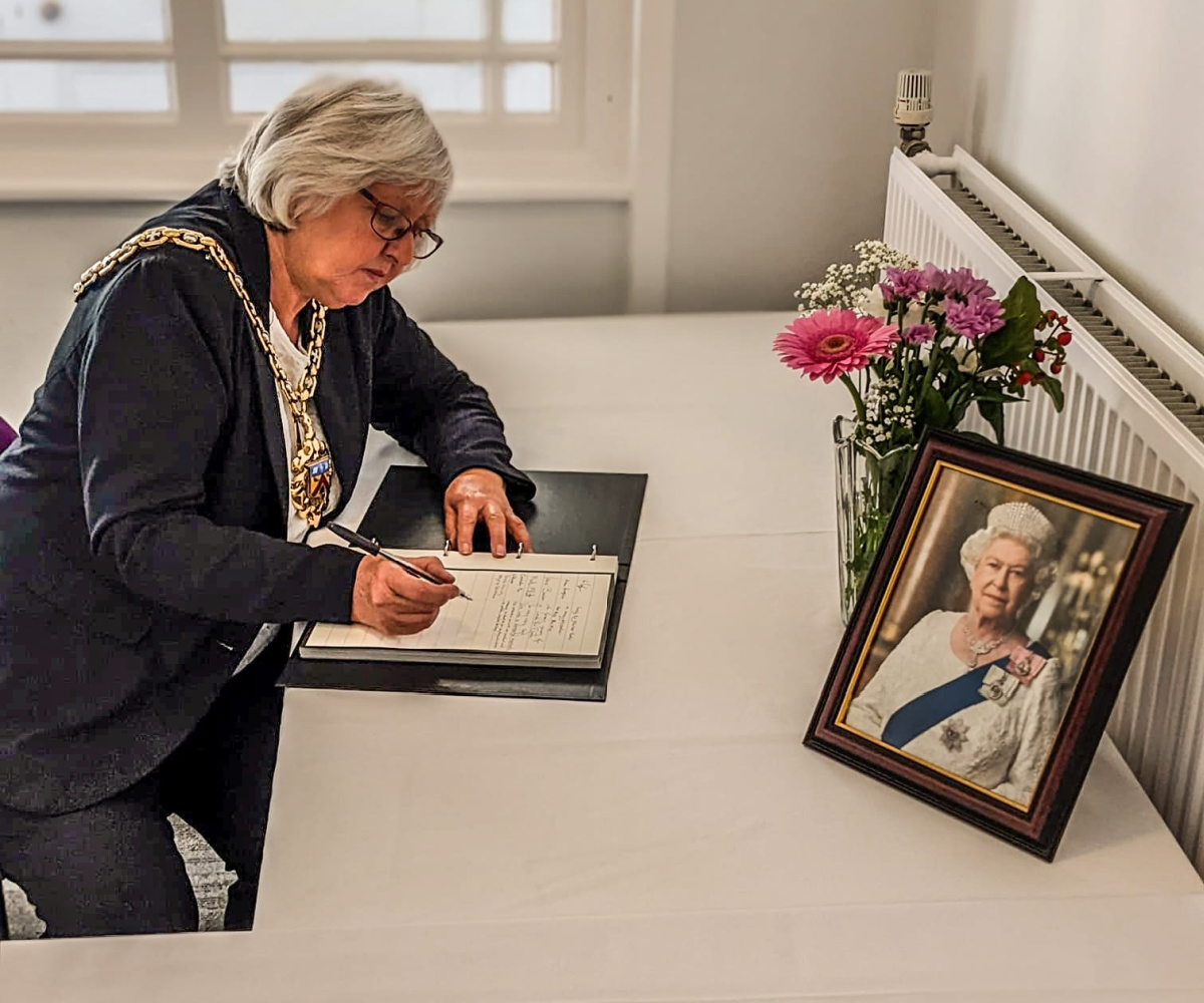 Image features Cheltenham Mayor, Cllr Sandra Holliday, writing a message of condolence at the Municipal Offices.